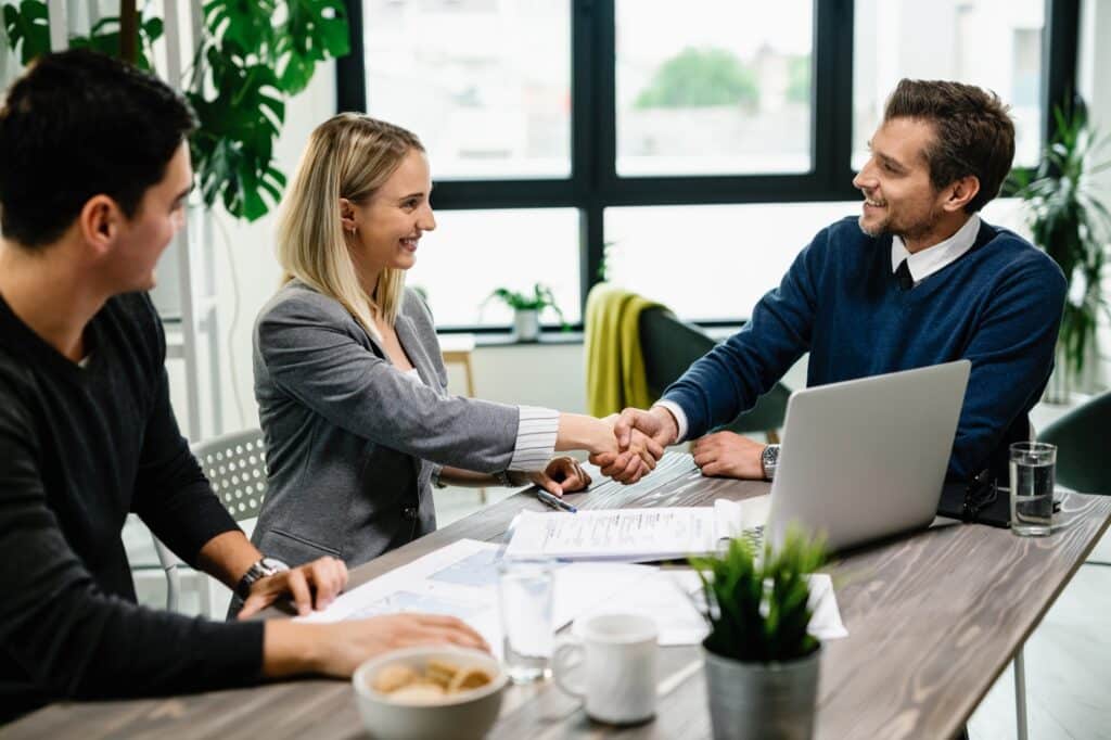 Clients and a professional advisor concluding a successful office consultation with a handshake